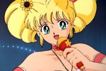 Sabrina, protagonista dell'anime "Ciao, Sabrina", è raffigurata mentre canta con un microfono colorato. Ha grandi occhi azzurri, capelli biondi raccolti in due grandi codini decorati con fiori, e indossa un abito rosa con collana e braccialetti. Sullo sfondo si intravede un palco illuminato.